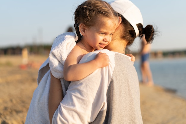 Mère étreignant avec sa petite fille en plein air dans la nature par une journée ensoleillée, émotions humaines positives, sentiments, émotions. Portrait de famille heureuse en vacances