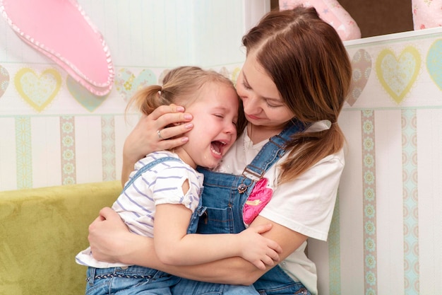 mère étreint sa fille qui pleure assise dans ses bras