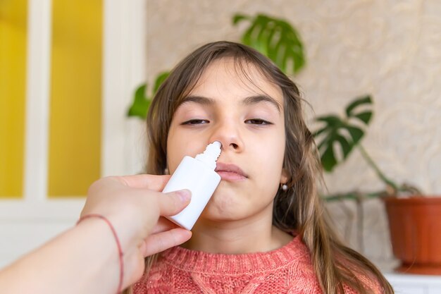 La mère fait couler des médicaments dans le nez de l'enfant. Mise au point sélective. Gens.