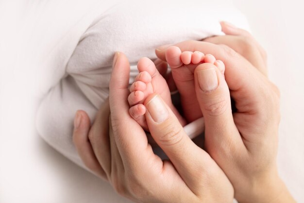 Mère fait un massage sur son pied de bébé Gros plan des pieds de bébé dans les mains de la mère sur un fond blanc Prévention du développement des pieds plats Dysplasie du tonus musculaire Famille amour soins et concept de santé