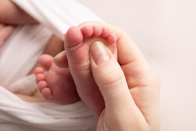 La mère fait un massage sur son pied de bébé. Gros plan des pieds de bébé dans les mains de la mère. Prévention des pieds plats, développement, tonus musculaire, dysplasie. Concepts de famille, d'amour, de soins et de santé. Macro d'atelier.