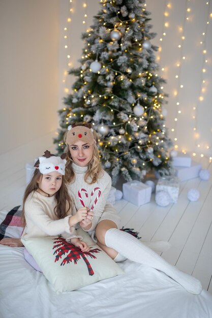 Mère de famille heureuse et fille d'enfant près de l'arbre de Noël à la maison