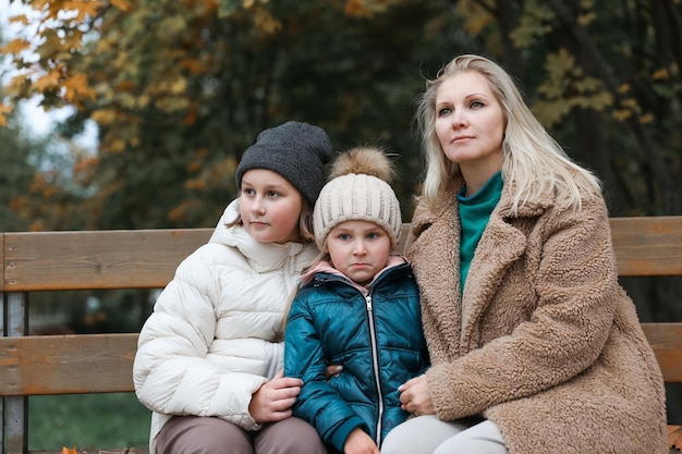 Une mère de famille heureuse et ses enfants se trouvent dans le parc de la ville d'automne Ils posent en souriant en jouant et en s'amusant Arbres jaune vif