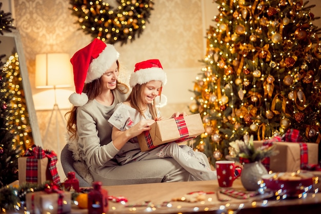 Une mère de famille heureuse et son enfant emballent des cadeaux de Noël