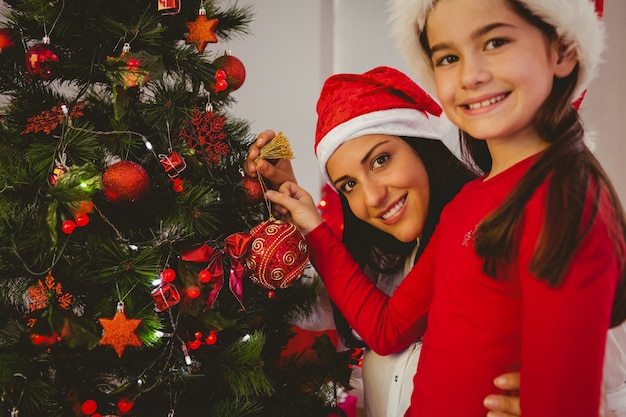 Mère et fille accroché des décorations de Noël sur l&#39;arbre