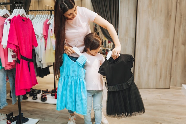 Mère et fille achètent des vêtements mère et petite fille essayant des vêtements dans le magasin