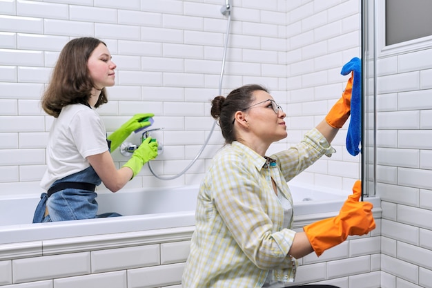 Mère et fille adolescente nettoyant ensemble dans la salle de bain. Fille aidant la mère à nettoyer à la maison. Adolescents et parents, relations, propreté et entretien ménager, tâches ménagères