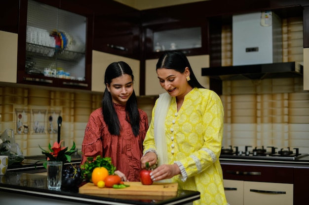 mère et fille adorable coupant la pomme dans le modèle pakistanais indien de cuisine