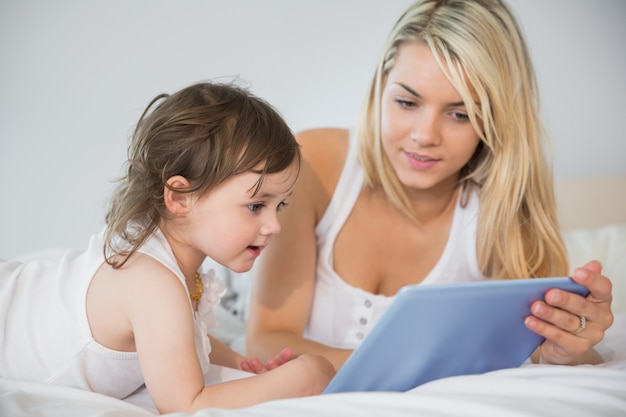 Mère et fille à l&#39;aide de tablette numérique sur le lit