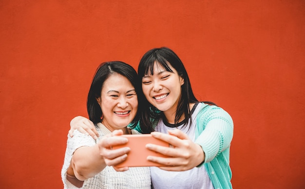 Mère et fille asiatique prenant selfie avec smartphone pour l'application de l'histoire