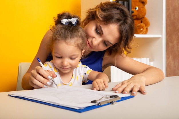 Mère et fille assise au bureau à faire leurs devoirs ensemble.