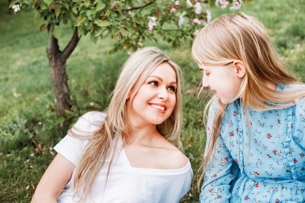 Mère et fille assise sur le sol sous un arbre en fleur