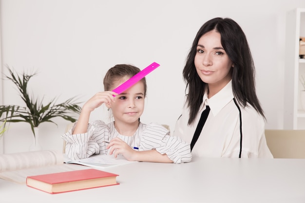 Mère et fille assises au bureau à faire leurs devoirs ensemble.