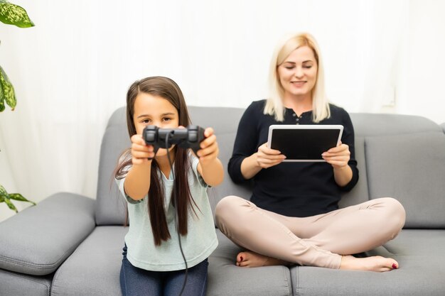 Mère et fille assises dans une salle de jeux, jouant à des jeux vidéo et s'amusant.