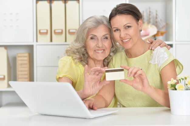 Mère et fille assises à table avec un ordinateur portable faisant des achats en ligne