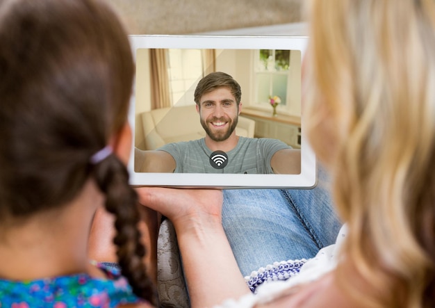 Mère et fille ayant un appel vidéo avec le père sur une tablette numérique