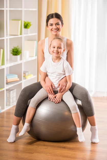 Mère et fille sur ballon de fitness à la maison.