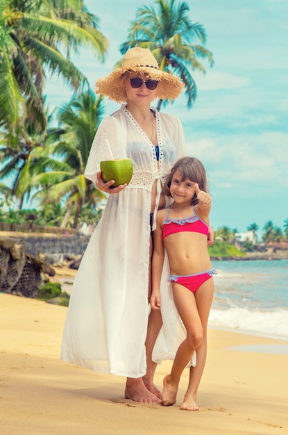Mère et fille boivent de la noix de coco sur la plage