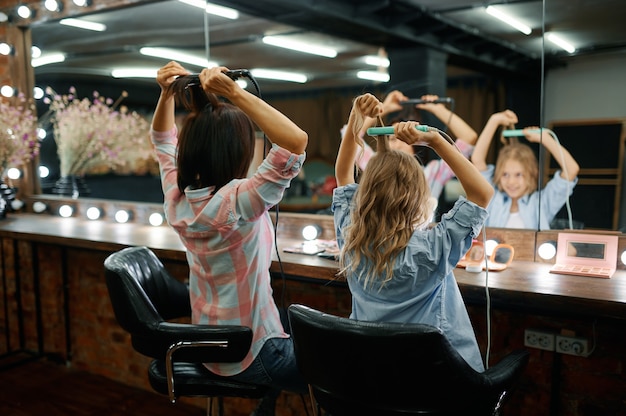 Mère et fille bouclent leurs coiffures dans un salon de coiffure
