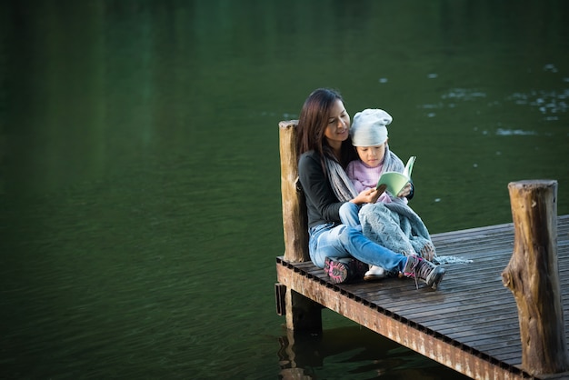 Mère et fille câlins, belle petite fille étreignant sa mère contre le lagon