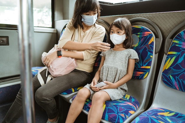 Mère et fille à cheval dans les transports publics pendant la pandémie portant un masque facial