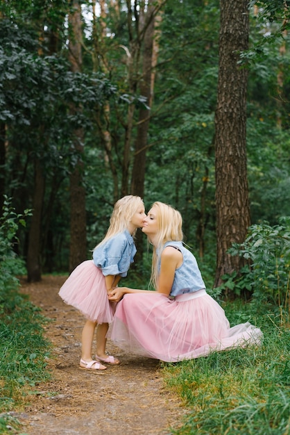 Une mère et une fille de cinq ans dans les mêmes vêtements romantiques se promènent dans le parc ou dans les bois.