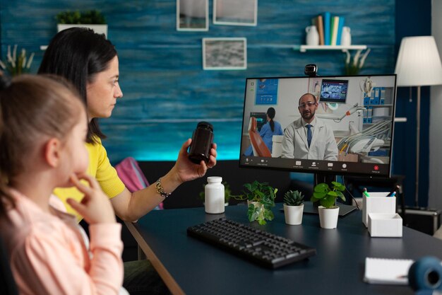 Photo mère et fille consultant un médecin par appel vidéo à la maison