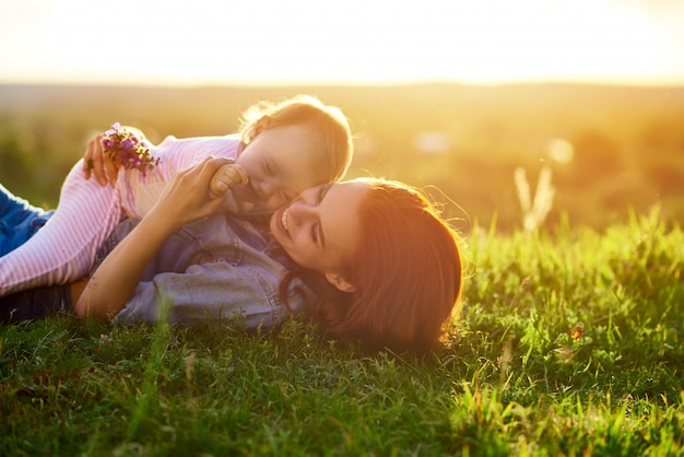 Mère et fille couché sur l&#39;herbe dans le champ pendant le coucher du soleil.