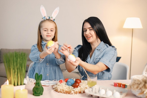 Mère et fille dans une cuisine lumineuse moderne et peindre ensemble des œufs de Pâques