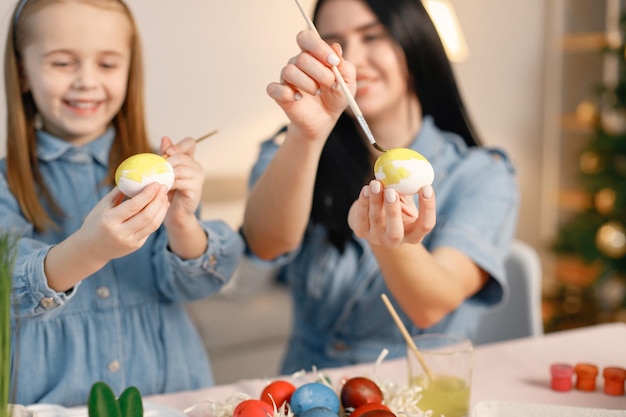 Mère et fille dans une cuisine lumineuse moderne et peindre ensemble des œufs de Pâques