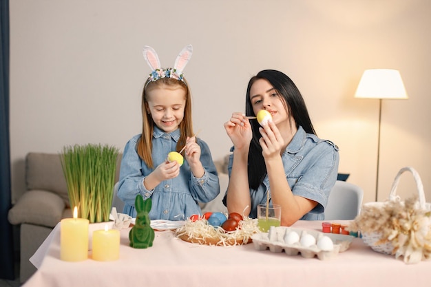 Mère et fille dans une cuisine lumineuse moderne et peindre ensemble des œufs de Pâques