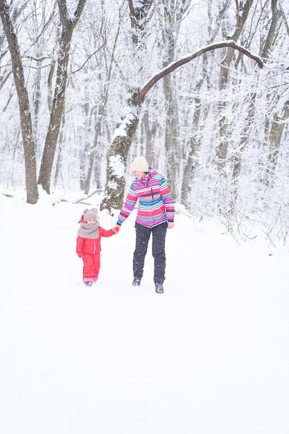 Mère et fille dans des vêtements colorés s'amusant lors d'une promenade d'hiver dans la nature