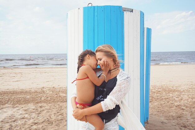 Photo mère et fille debout sur la plage