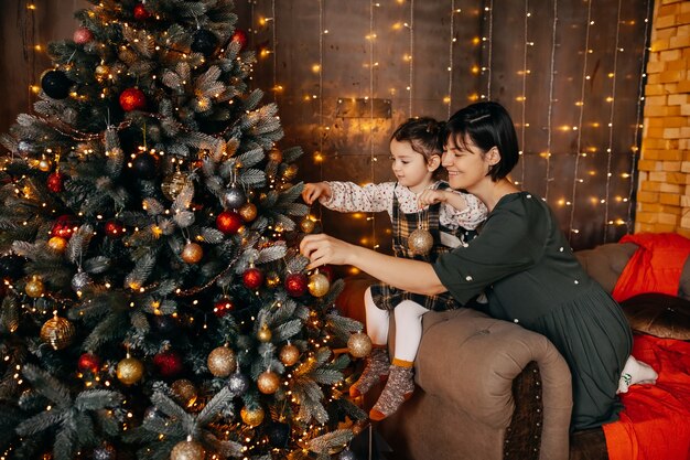 Mère et fille décorant l'arbre de Noël à la maison