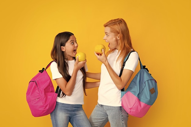 Mère et fille écolières avec sac d'école prêt à apprendre Retour à l'école Maman et enfant sur fond de studio jaune isolé Éducation familiale