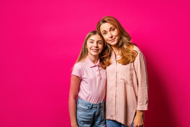 Mère et fille embrassant sur mur rose