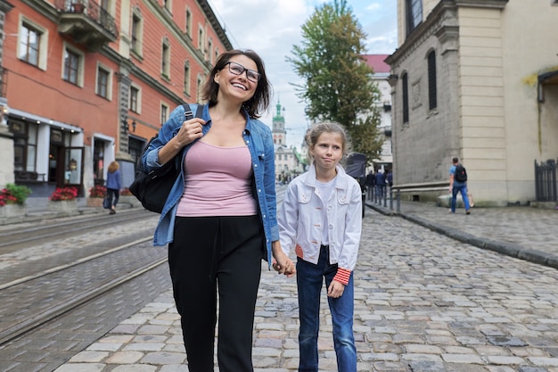 Mère et fille enfant 8, 9 ans marchant ensemble le long de la rue de la vieille ville se tenant la main