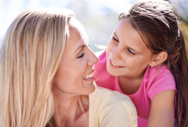 Mère fille enfant et bonheur en plein air avec l'attachement pour le soutien câlin et la confiance en vacances dans la nature femme de famille et fille avec le visage sourire et embrasser en vacances voyages et l'amour avec plaisir