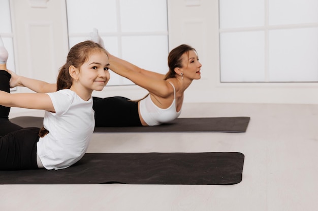 Mère et fille enfant dans le centre de gym faisant des exercices de yoga fitness stretching