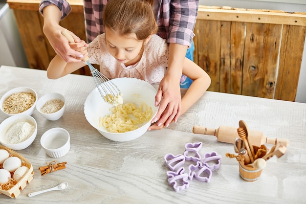 Mère fille d'enseignement préparer la pâte ensemble dans la cuisine