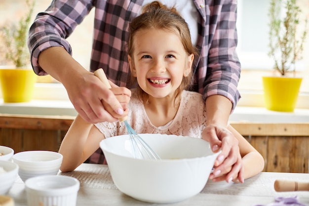 Mère fille d'enseignement préparer la pâte ensemble dans la cuisine