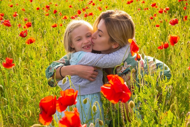 Mère et fille étreignant sur un champ de coquelicots en fleurs Vacances en famille d'été sur la nature Été sur une prairie de coquelicots avec des fleurs de coquelicots