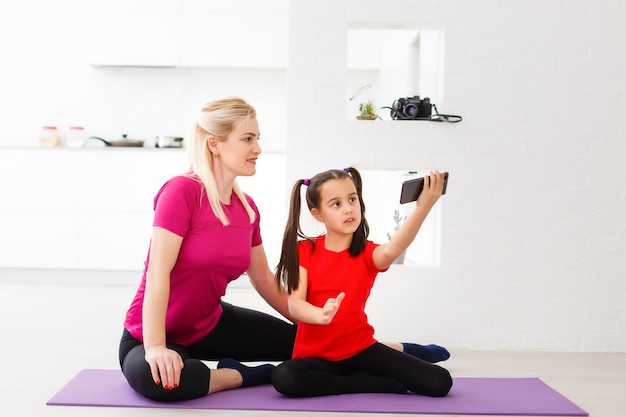 Mère et fille faisant des exercices de yoga sur tapis à la maison.