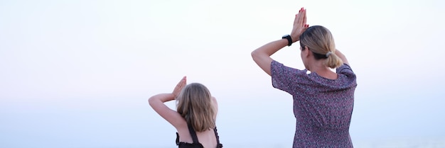 Mère et fille font du yoga méditer en position du lotus sur la plage