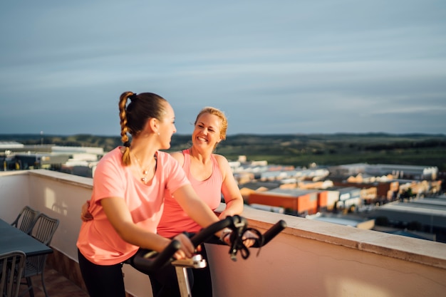 Mère et fille font des exercices de vélo sur la terrasse de la maison