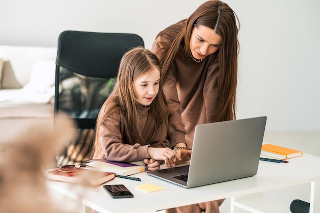 Mère et fille font leurs devoirs sur l'ordinateur portable