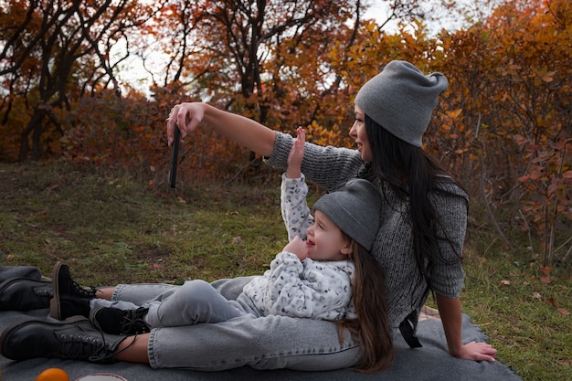 Mère Et Fille Font Des Selfies Sur Leur Smartphone En Arrière-plan Du Parc D'automne