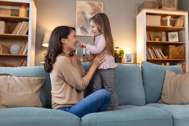 Une mère et une fille heureuses et souriantes se reposent et passent du temps ensemble pendant les vacances. Une femme heureuse et calme et son enfant assis sur un canapé et étreints dans une pièce de leur maison familiale.