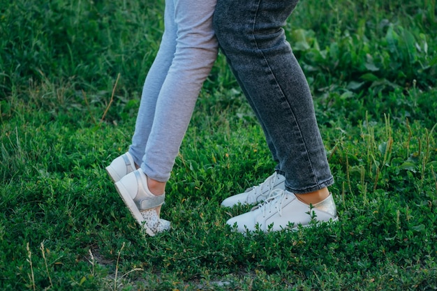 Mère et fille jambes et chaussures sur l'herbe seulement les pieds