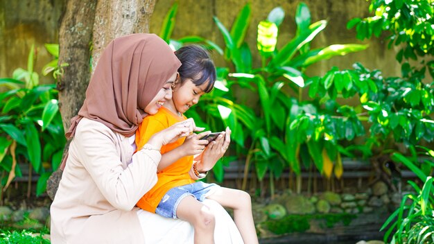 Mère et fille jouant au téléphone dans le parc